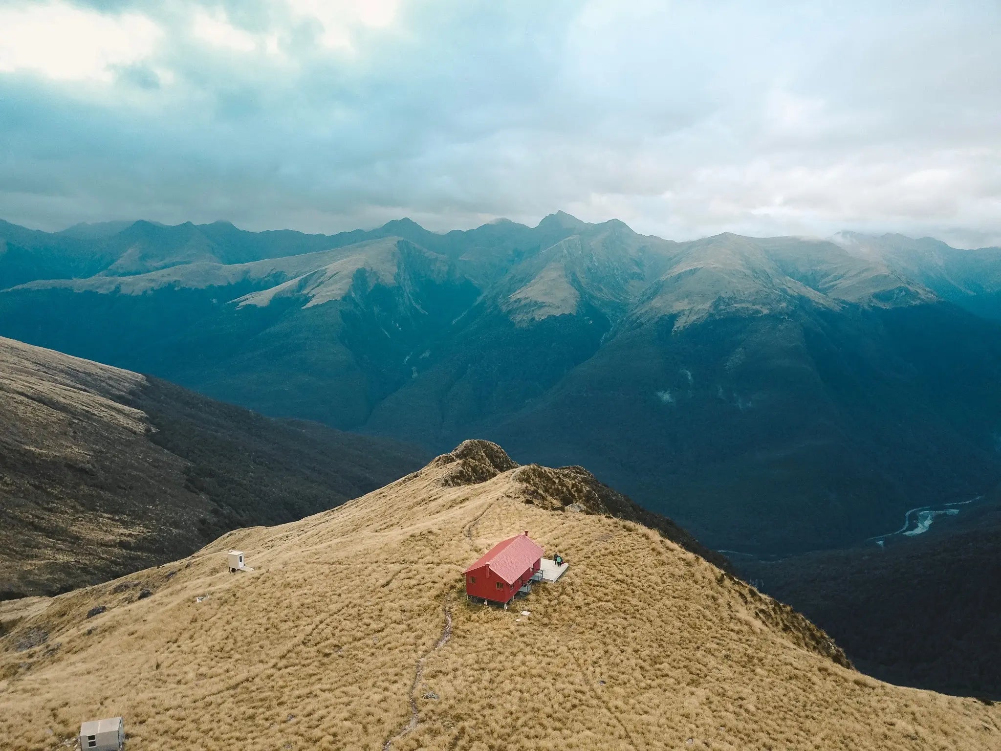 A red alpine hut overlooking mountains in Aotearoa
